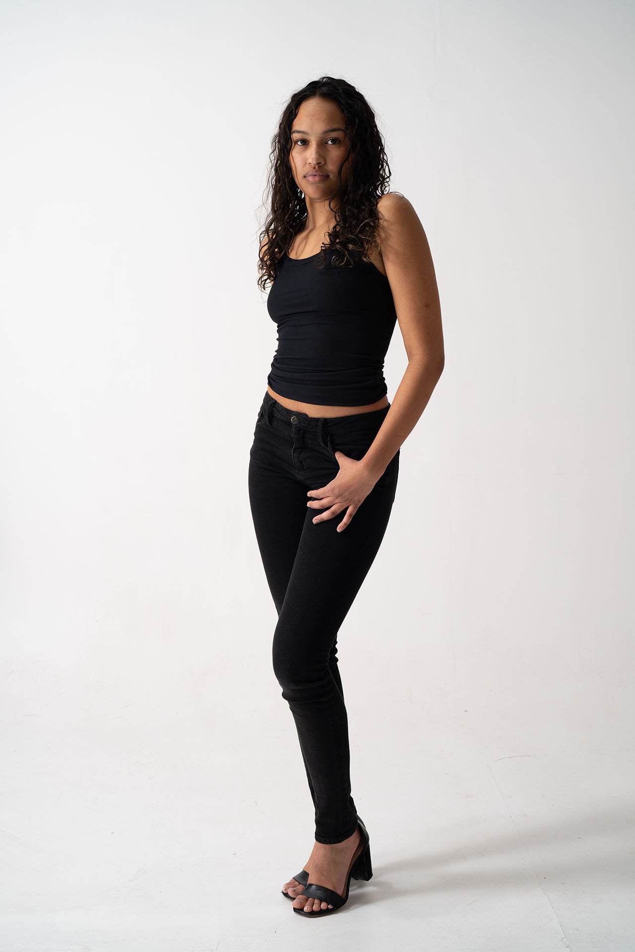 Model in black tank top and jeans, alternate angle portfolio digital shot on white background