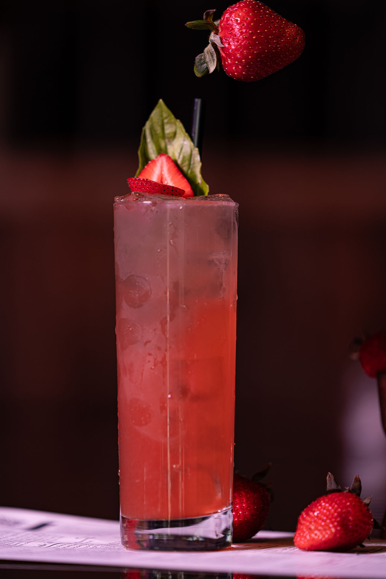 Basil Bourbon Smash cocktail garnished with strawberry and basil, at Pretty Neat Bar
