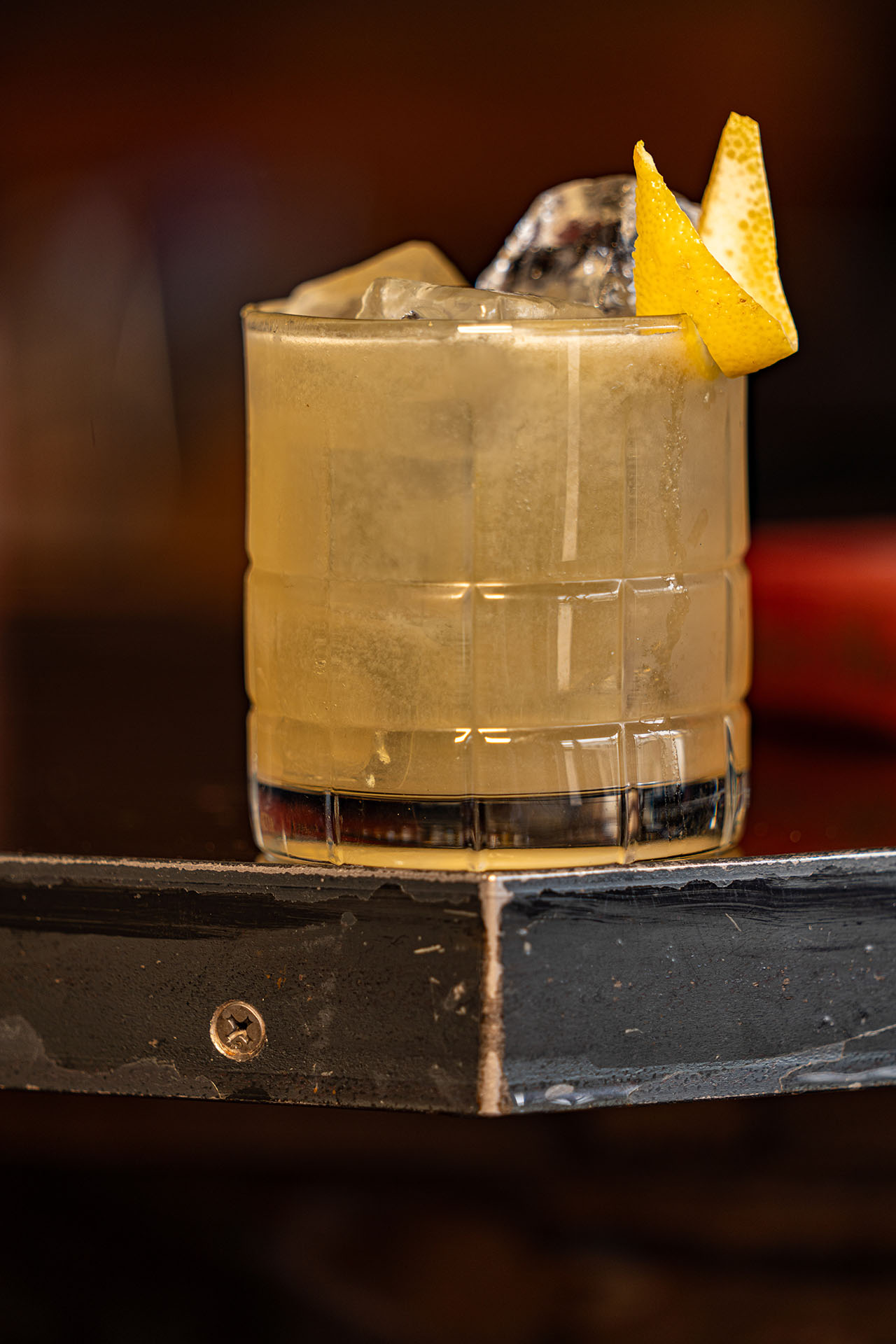 Bees Knees cocktail with an orange twist garnish on a dark wood bar, at Pretty Neat Bar