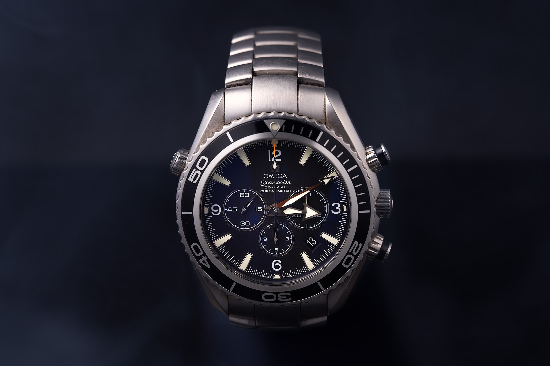 Product photo of a stainless steel chronograph watch against a dark background with dramatic lighting