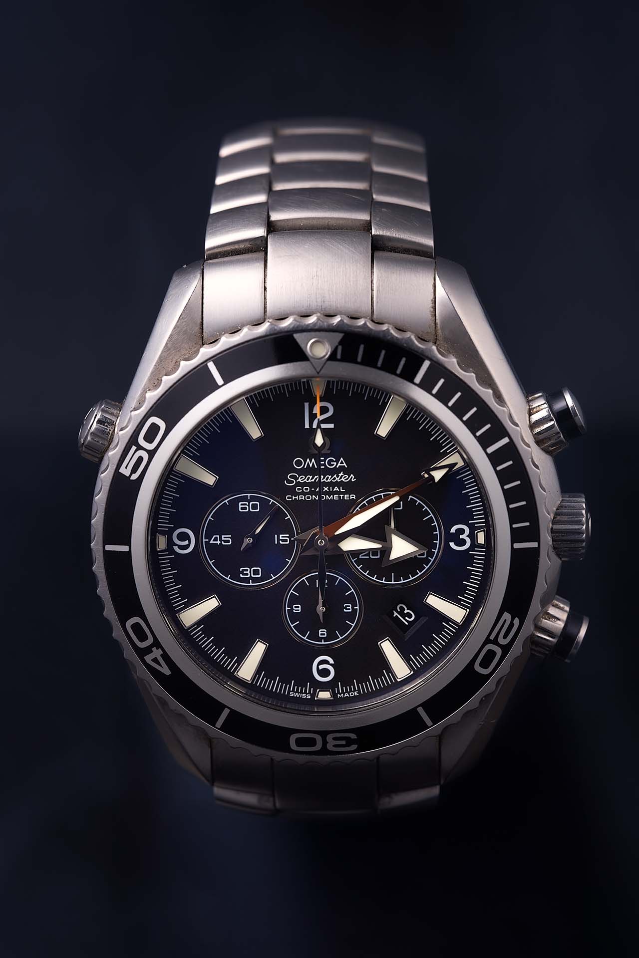 Close-up product photo of a stainless steel dive watch face with dark moody lighting