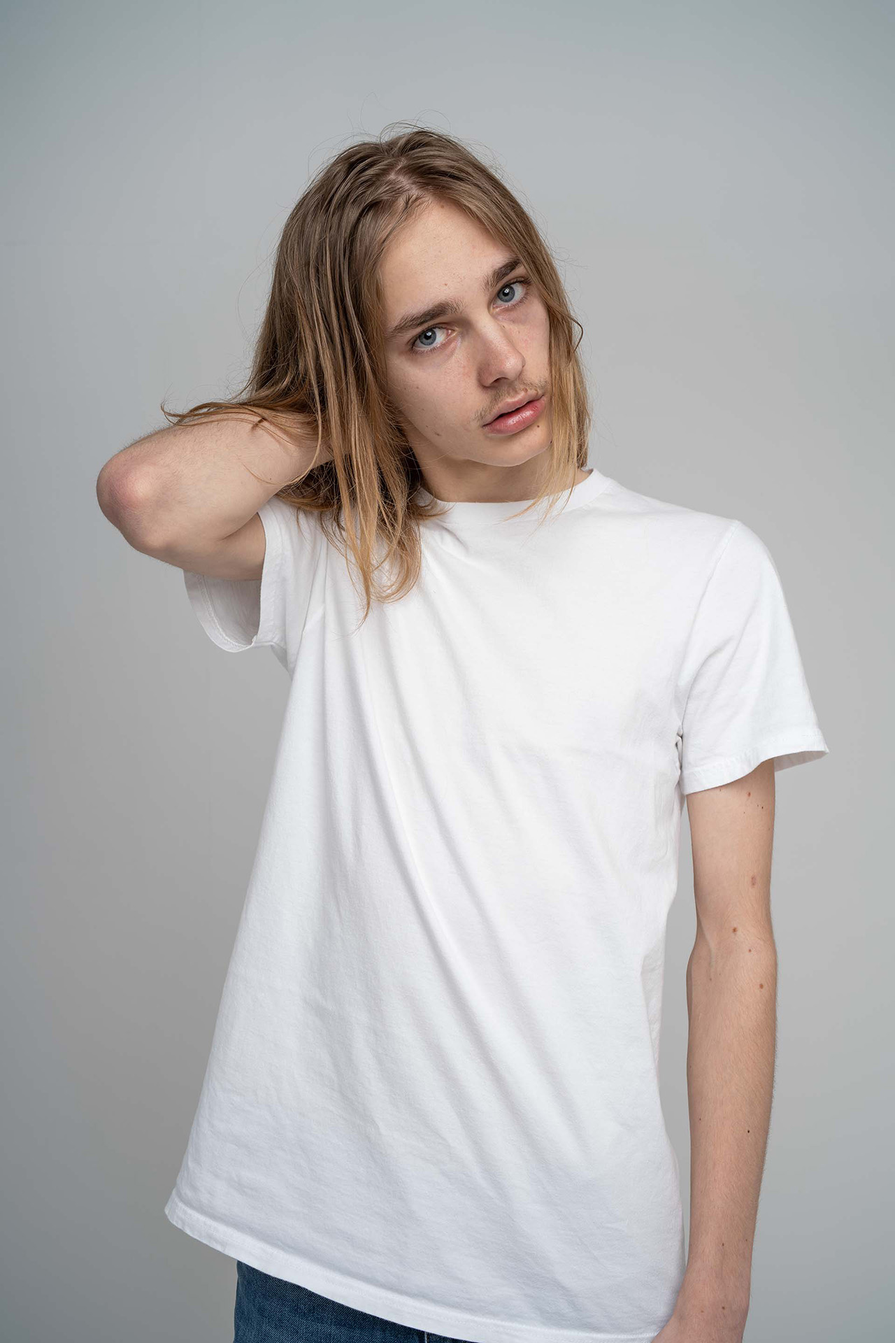 Male model portfolio digital with hand behind head, long hair, white t-shirt