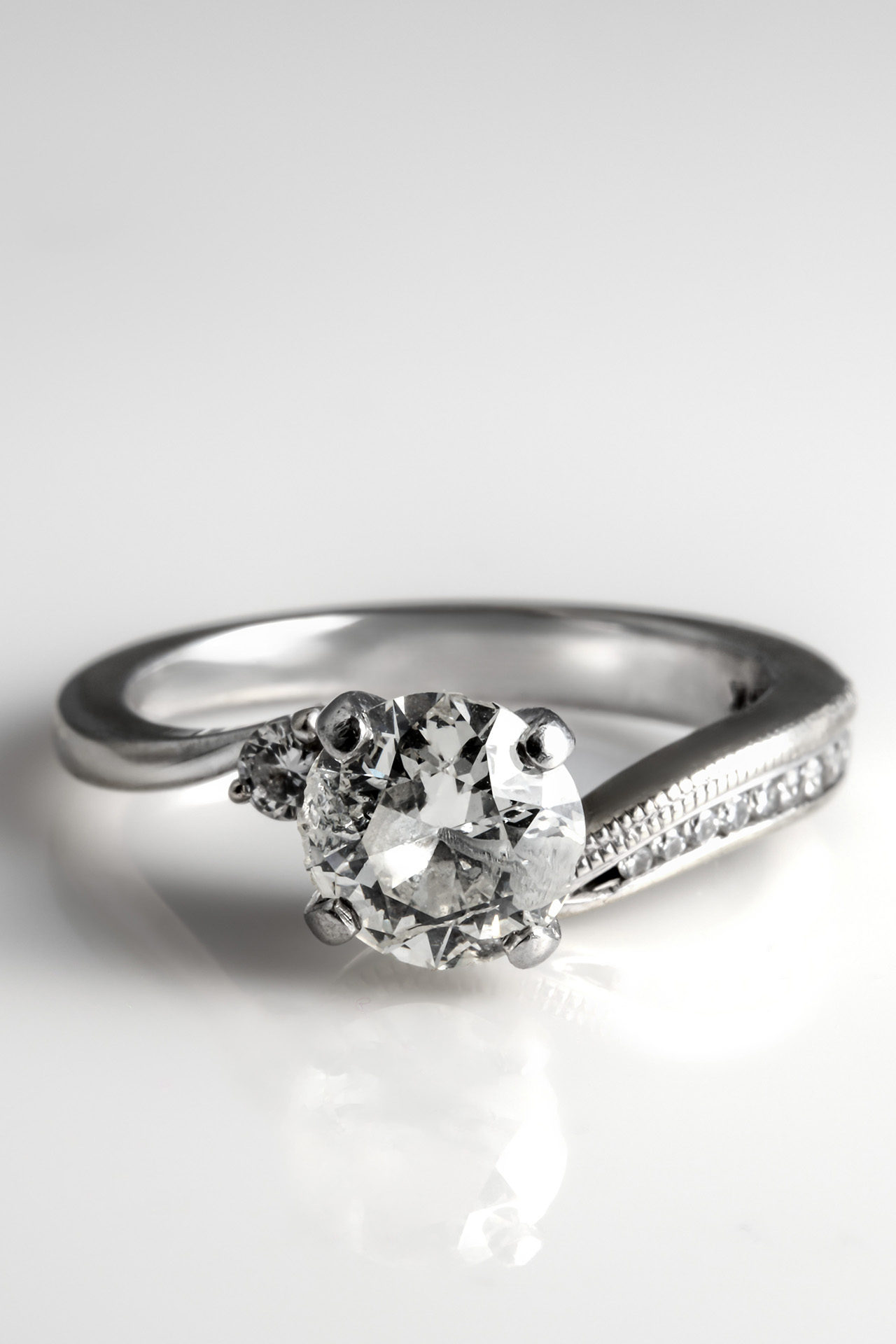 Vertical crop product shot of a diamond engagement ring with a pavé band