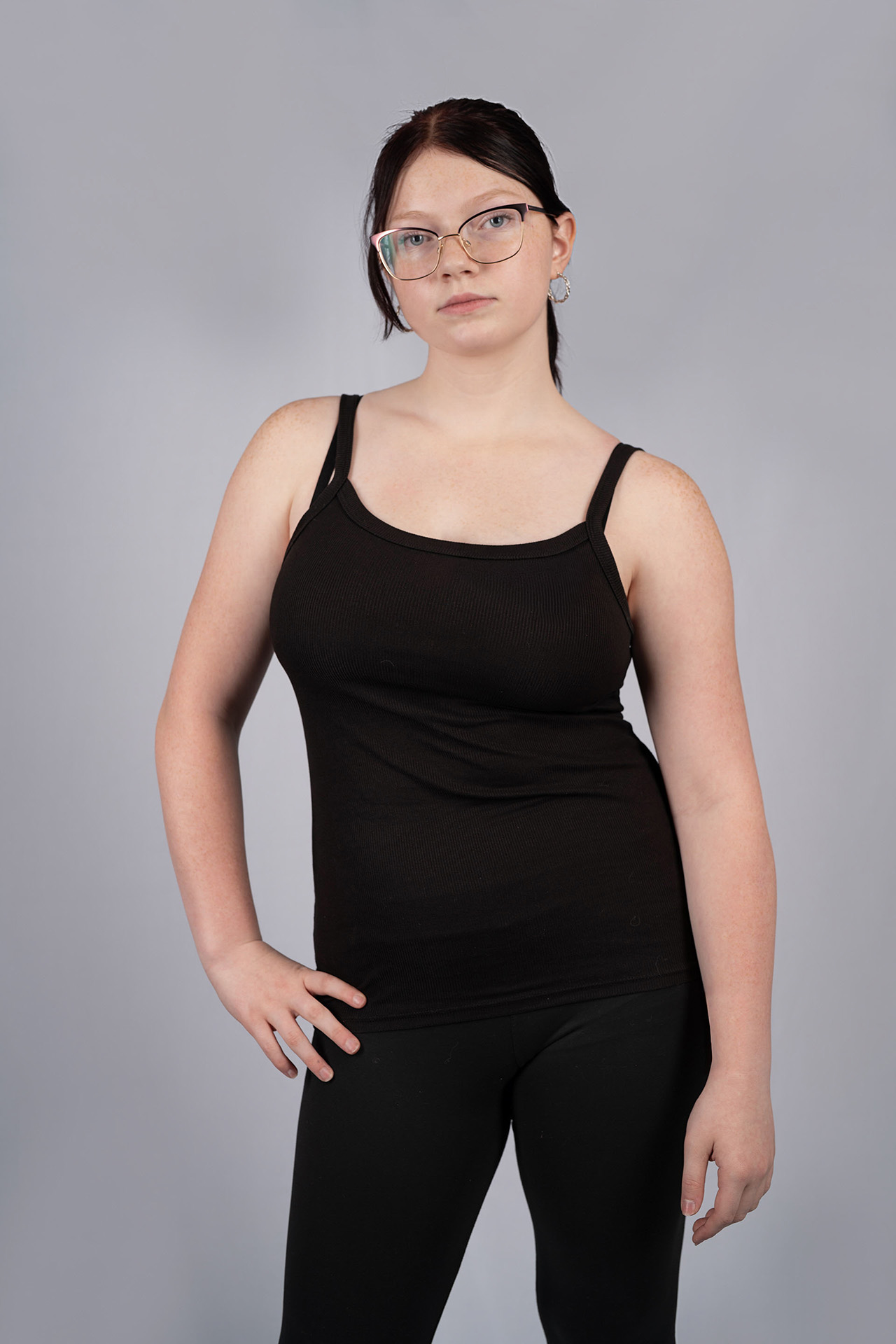 Full-body model portfolio digital in glasses, black tank top and leggings, hand on hip
