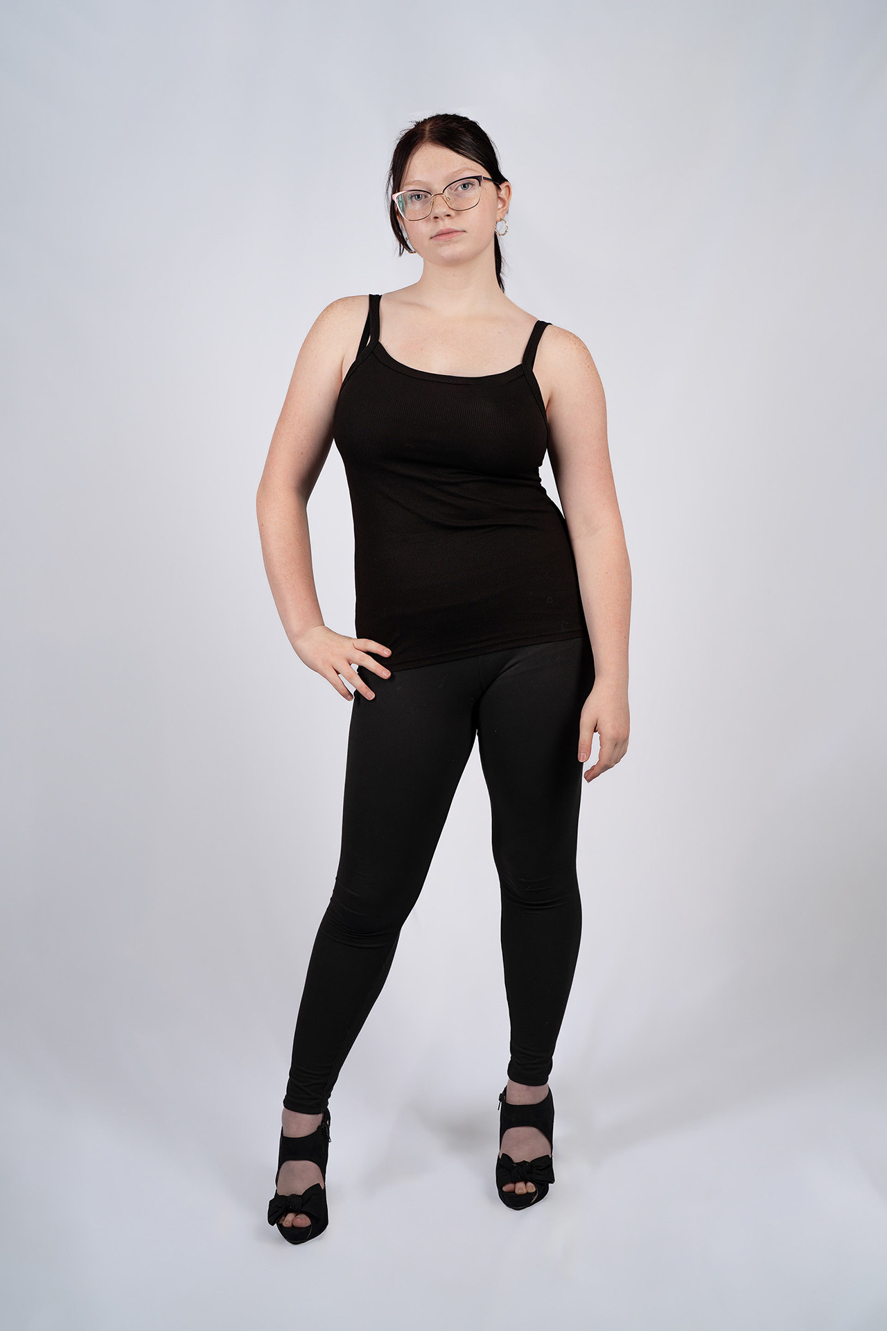Full-body model portfolio digital in glasses, black tank top, leggings, and heels, standing pose
