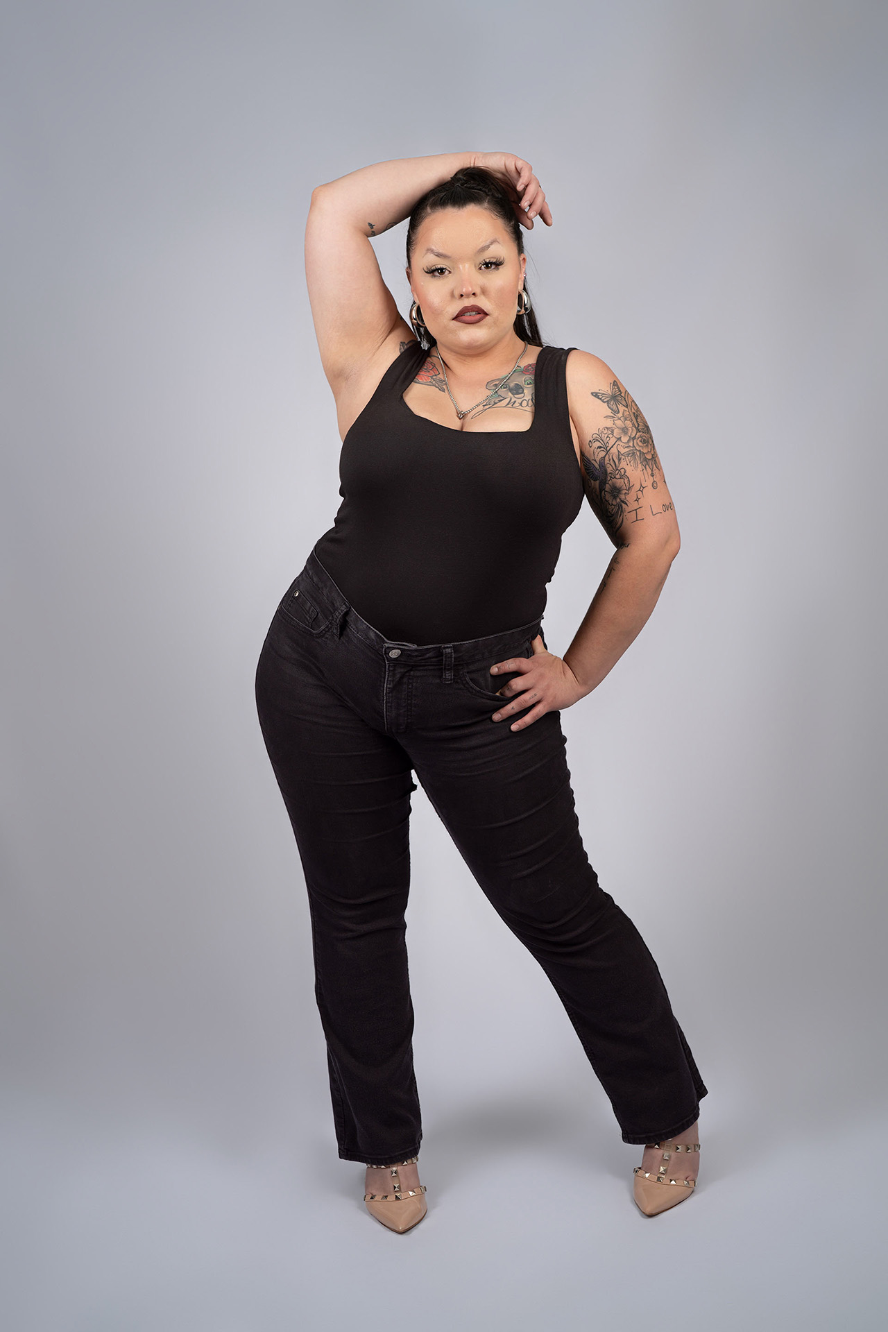 Full-body model portfolio digital with hand near her head, black outfit, plus-size model