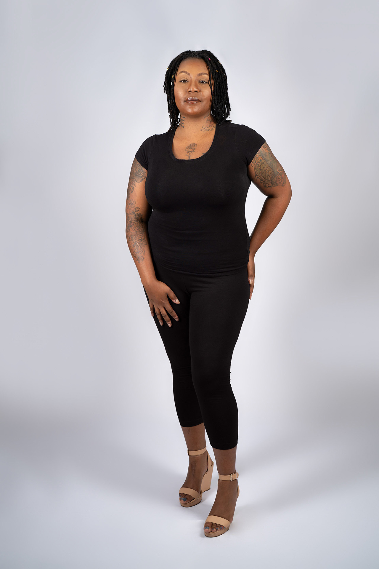 Full-body model portfolio digital standing in black outfit and heels, neutral background