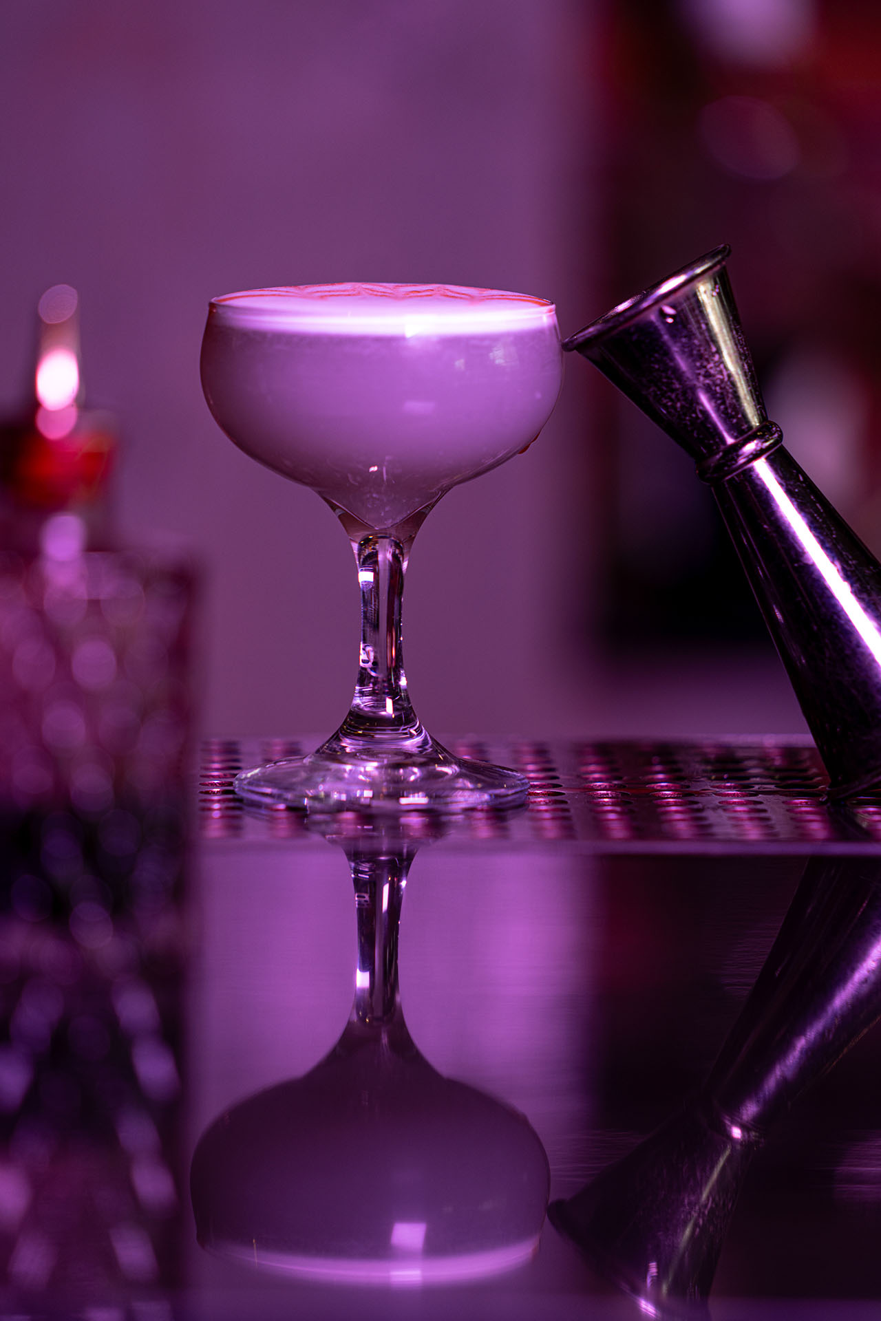From Risa with Love cocktail in an hourglass-shaped glass with dramatic moody lighting, at Pretty Neat Bar