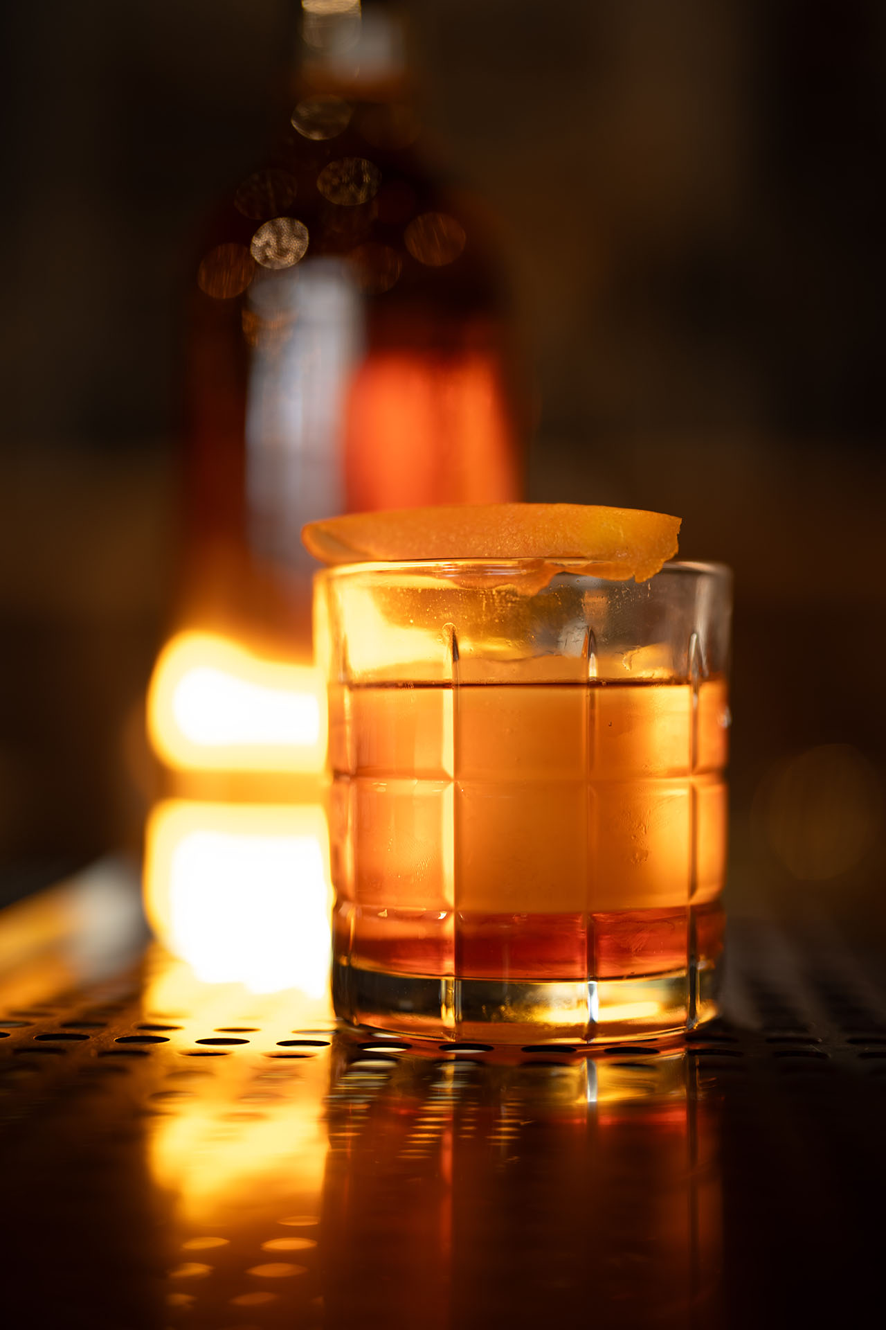 Holliday Olde Fashioned cocktail with an orange peel garnish and a warm fire glow, at Pretty Neat Bar