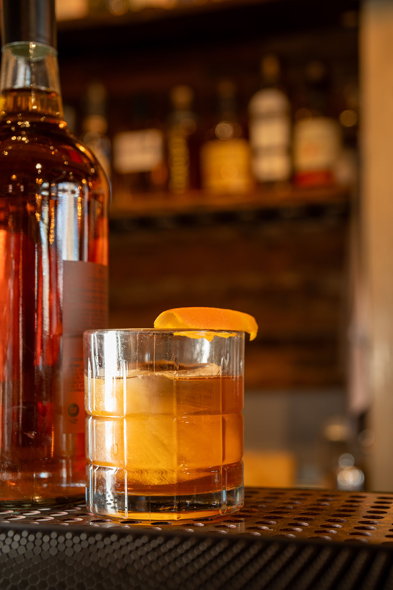 Holliday Olde Fashioned cocktail styled beside its bottle, at Pretty Neat Bar