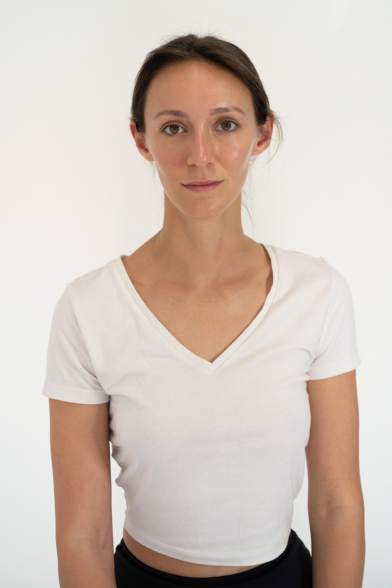 Model portfolio digital headshot in a white v-neck t-shirt, neutral front-facing expression