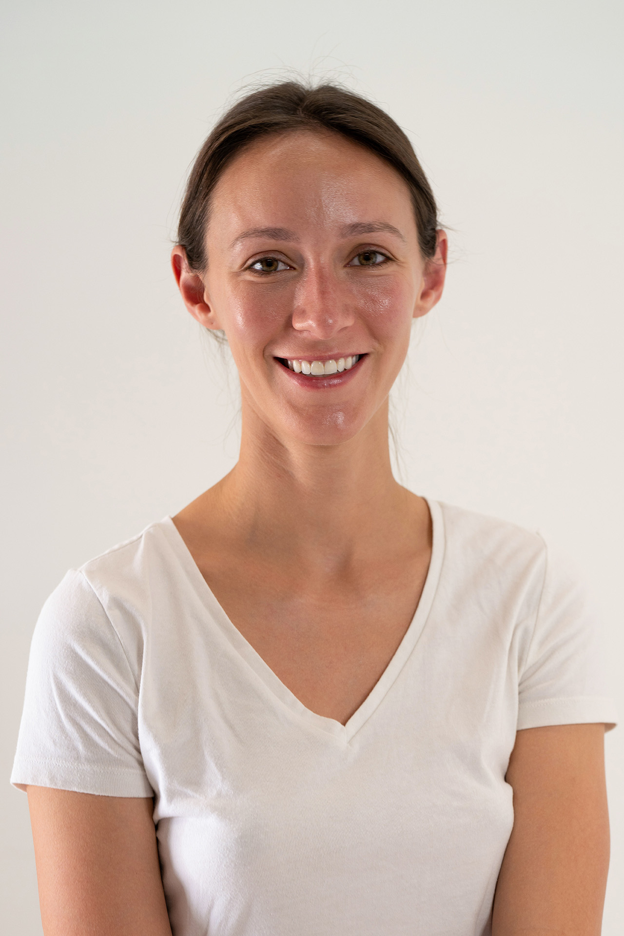 Smiling model portfolio digital headshot in a white v-neck t-shirt, front-facing