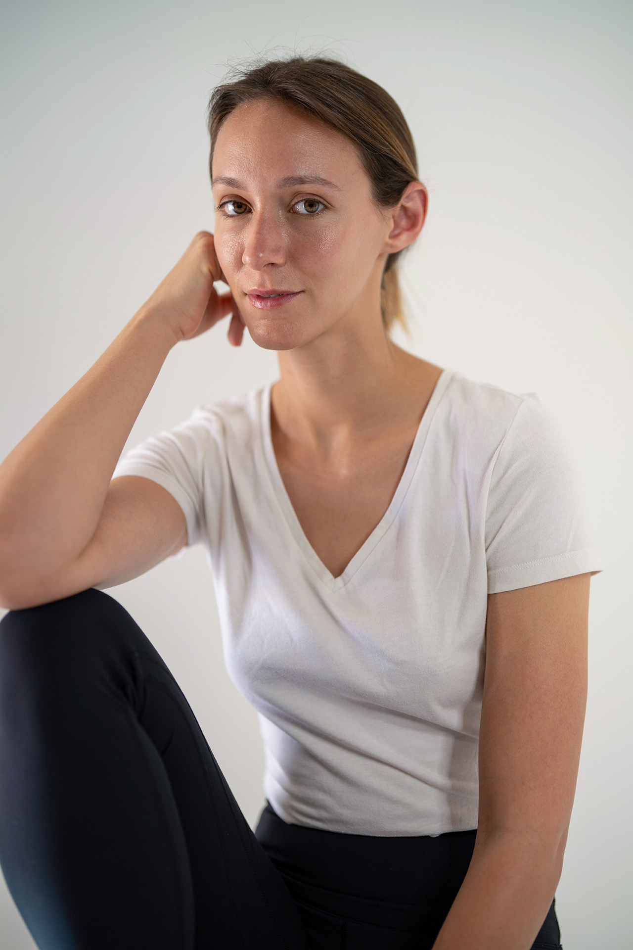 Seated model portfolio digital with hand resting near her head, thoughtful expression