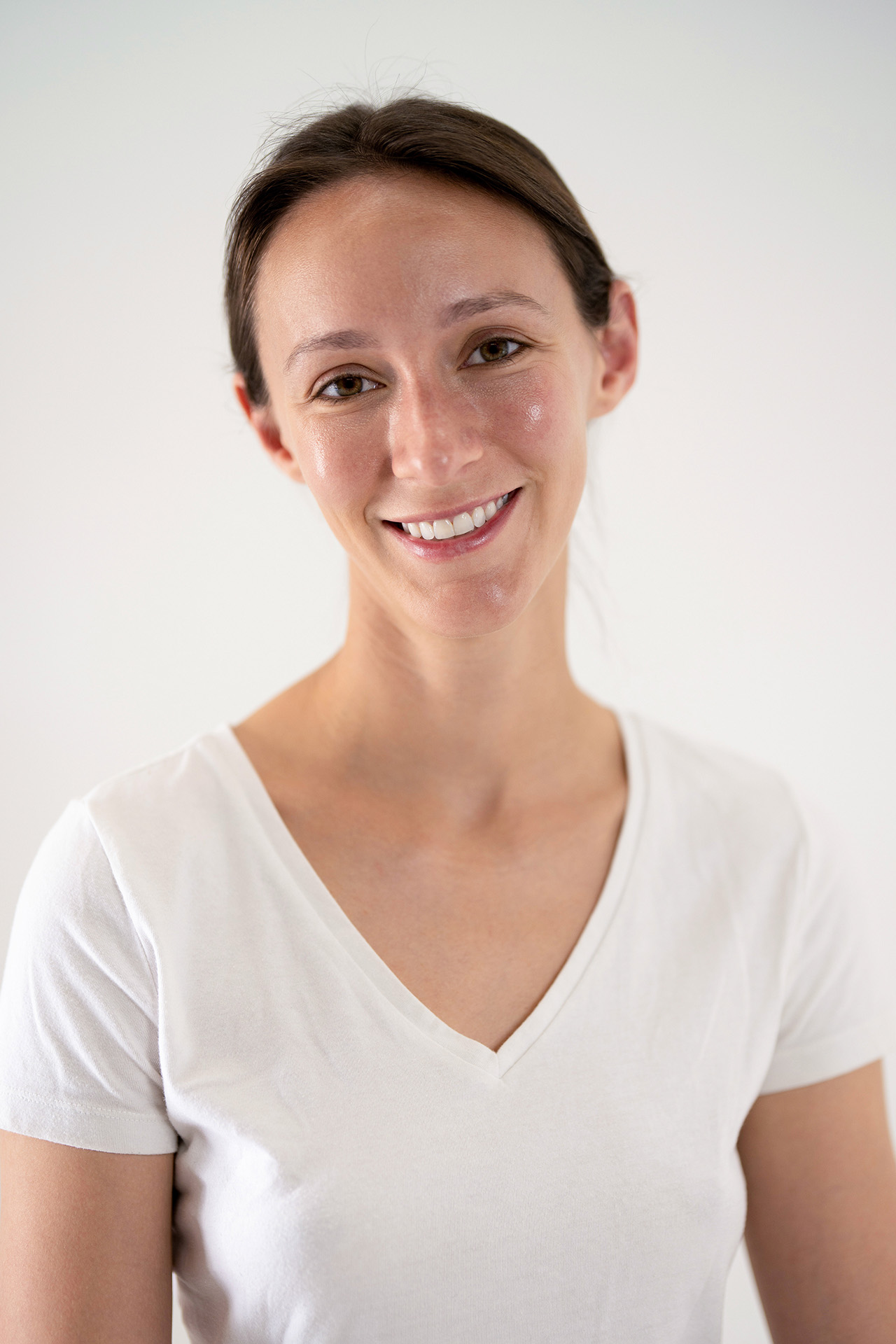 Smiling model portfolio digital headshot, alternate angle, white v-neck t-shirt