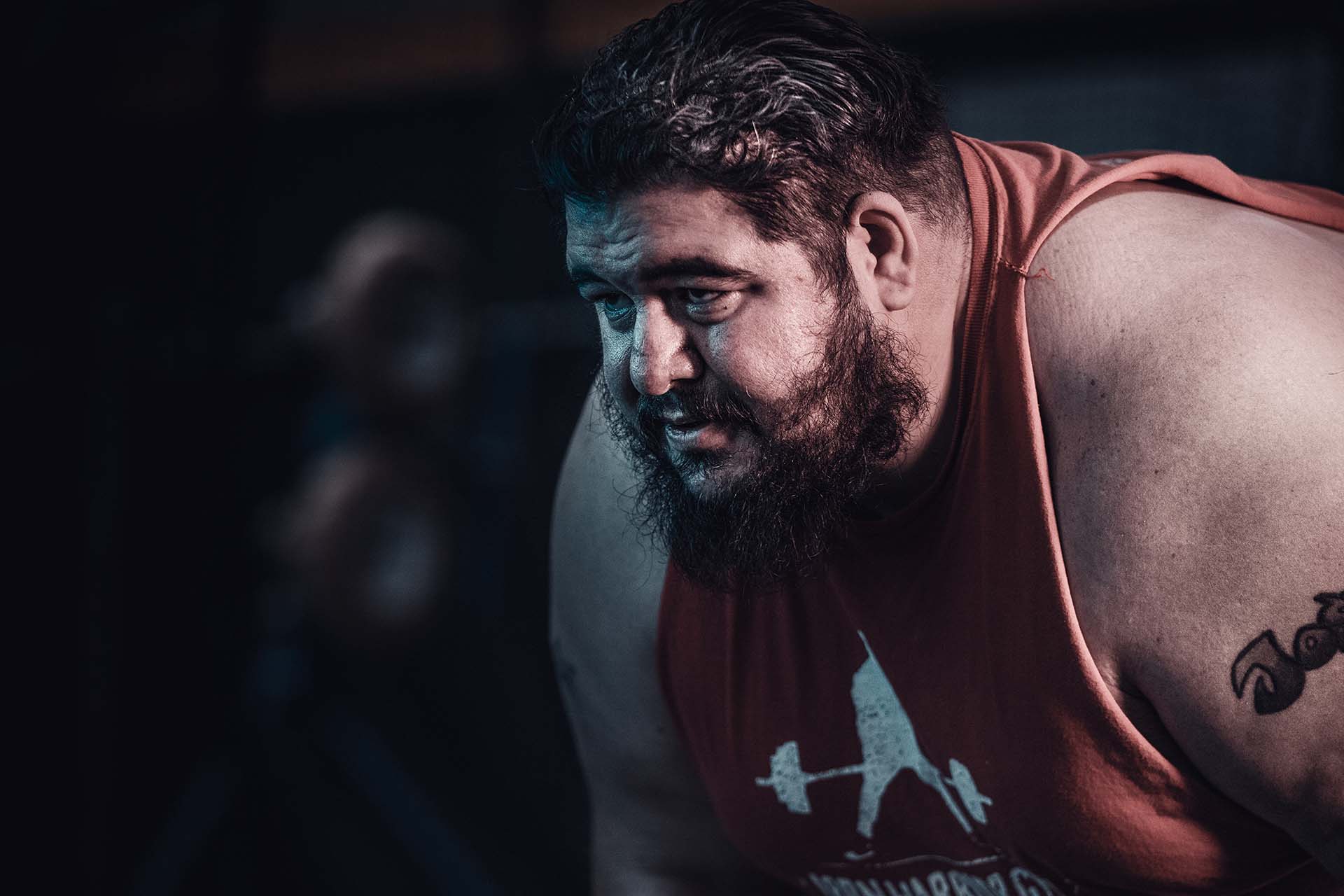 Close-up moody portrait of a bearded weightlifter in a gym, dramatic low-key lighting, Denver photography