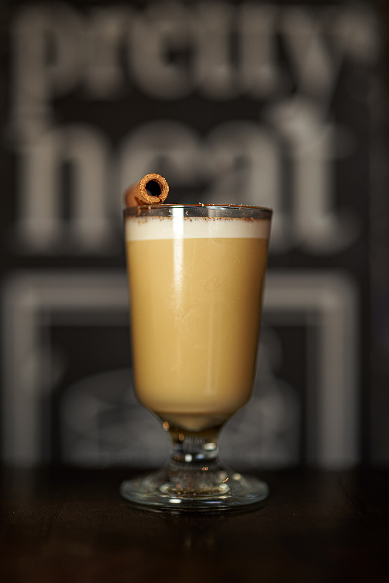 Pretty Neat Eggnog cocktail in a glass mug in front of the bar's signage, at Pretty Neat Bar