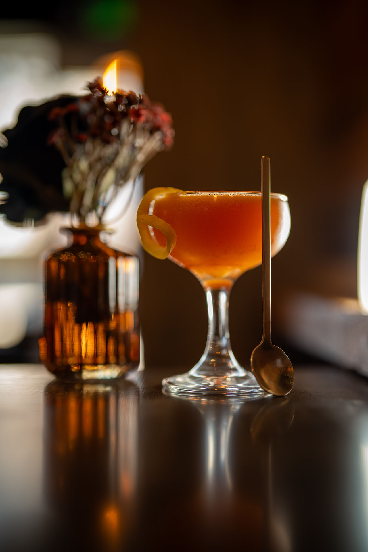 Pumpkin Patch Kids cocktail with an orange twist garnish, candlelit styling, at Pretty Neat Bar